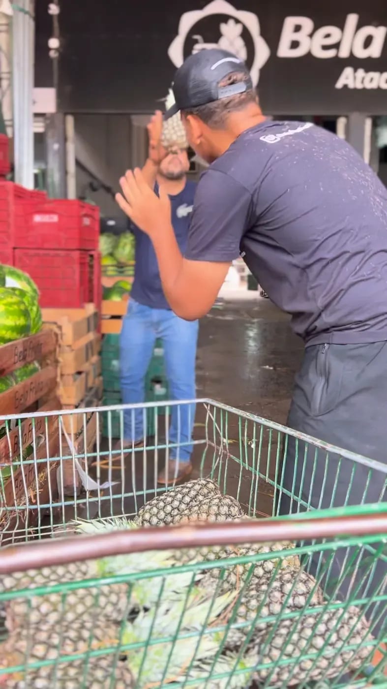 Funcionário com camiseta da Bela Fruta separando abacaxis no galpão.